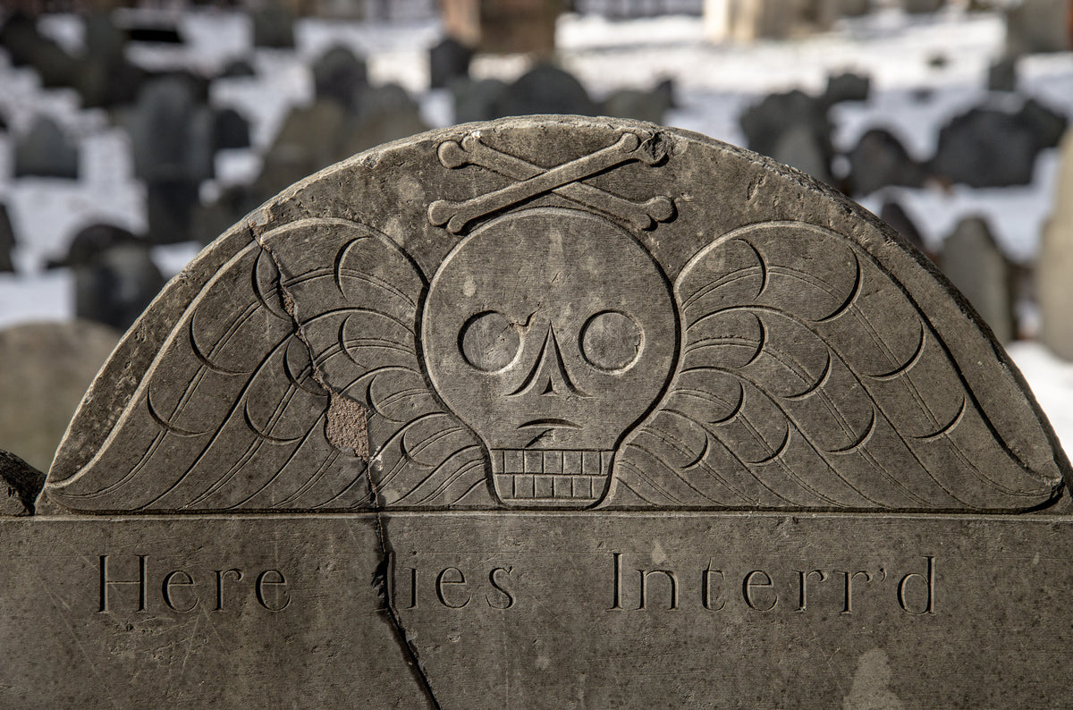 Winged death’s head and crossed bones carved into an early New England gravestone
