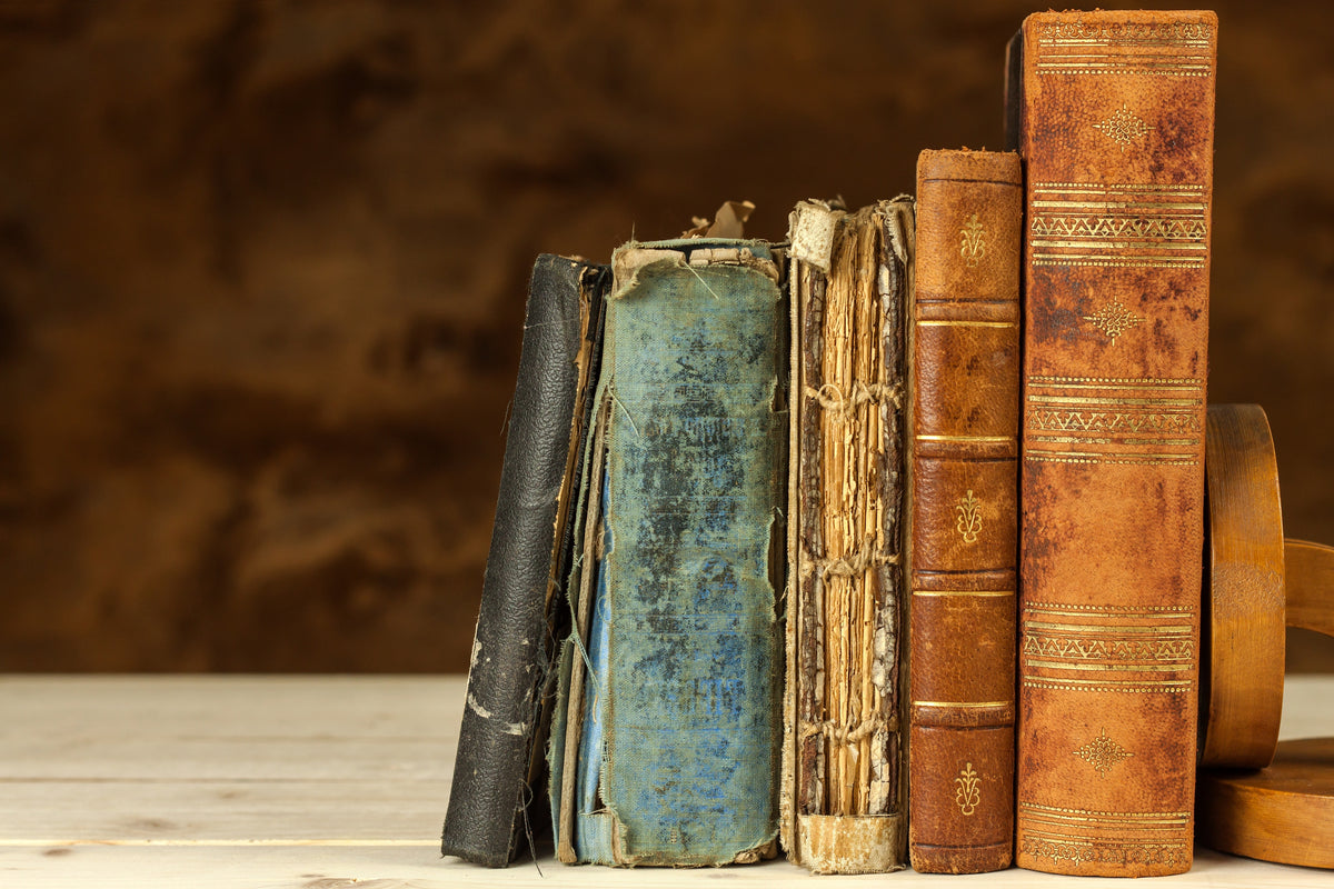 A collection of worn antique books with leather and cloth bindings.